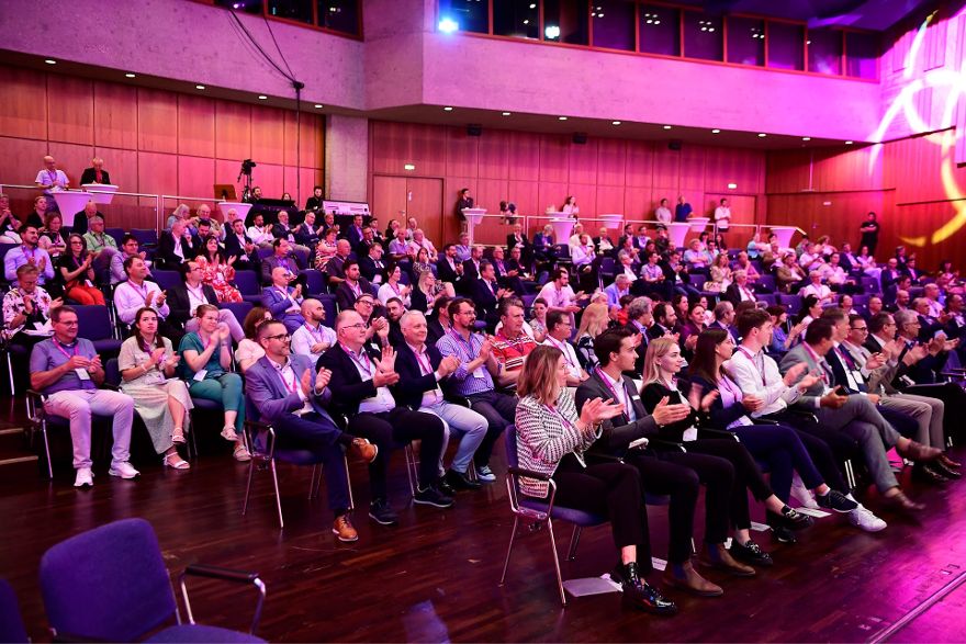 Mehrere Reihen sitzender Menschen, die konzentriert in eine Richtung schauen und klatschen.